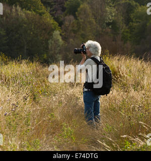 Une femme photographe à l'aide de son appareil photo pour capturer des images dans la campagne Banque D'Images