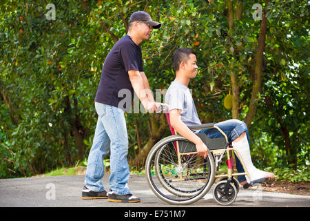 Jeune homme assis sur un fauteuil roulant avec son frère Banque D'Images