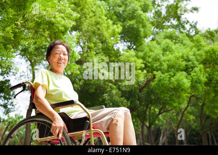 Asian senior femme assis sur un wheelchai dans le parc Banque D'Images