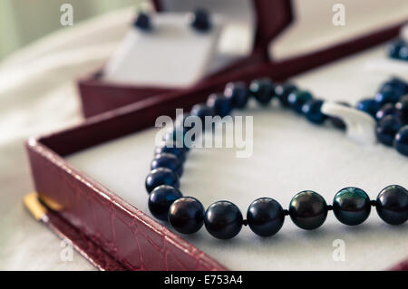 Un collier de perles noires dans une boîte à bijoux rouge Banque D'Images