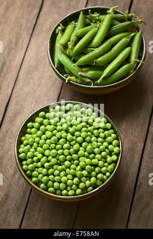 Pois (lat. Pisum sativum) et fermées dans des bols peapods (Selective Focus, Focus sur la moitié inférieure de l'pois dans le bol) Banque D'Images