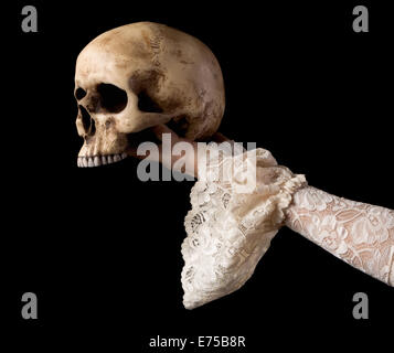 Crâne humain Creepy tenue par une femme portant la main manches dentelles anciennes Banque D'Images