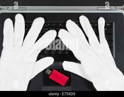 Vue de dessus gros plan d'un des gants blancs et une clé USB en haut de clavier de l'ordinateur Banque D'Images