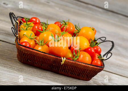 L'angle de vue sur le jardin tomates fraîches dans panier sur planches de bois rustique Banque D'Images