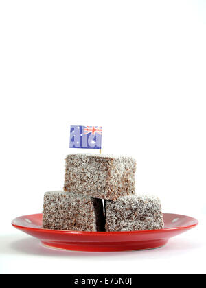 Gâteau traditionnel Australien, Lamingtons, sur la plaque rouge à pois avec drapeau australien sur un fond blanc. Banque D'Images