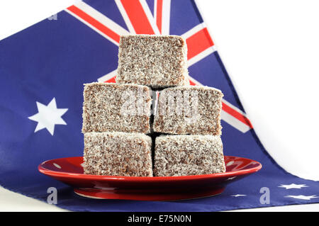 Gâteau traditionnel Australien, Lamingtons, sur la plaque rouge à pois avec drapeau australien sur un fond blanc. Banque D'Images