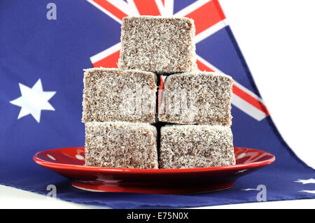 Gâteau traditionnel Australien, Lamingtons, sur la plaque rouge à pois avec drapeau australien sur un fond blanc. Banque D'Images