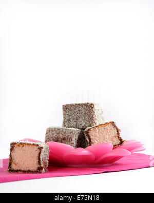 Gâteau traditionnel Australien, Lamington, sur la plaque et serviette rose sur un fond blanc. Banque D'Images