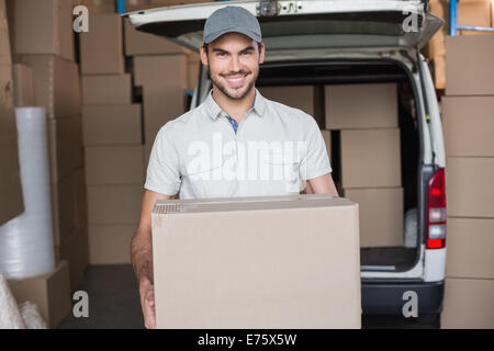 Chauffeur de livraison smiling at camera holding box Banque D'Images