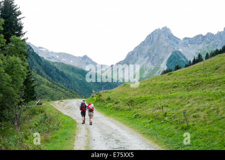 LA BALME, FRANCE - Le 25 août : tour du Mont Blanc les randonneurs sur route de campagne, avec aiguilles Pennaz en arrière-plan. L'excursion crosse Banque D'Images