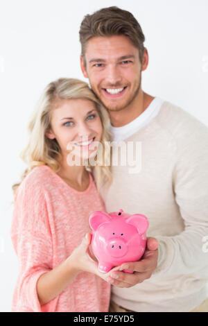 Portrait of attractive young couple holding piggybank Banque D'Images
