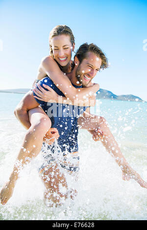 Woman riding piggy back sur petit ami dans l'eau Banque D'Images