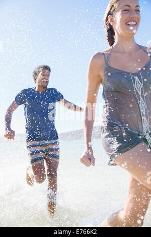 Couple splashing in water on beach Banque D'Images