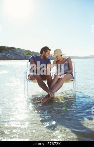 Couple assis dans des chaises dans les vagues Banque D'Images
