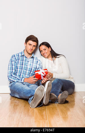 Young couple sitting on floor with gift Banque D'Images