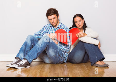 Young couple sitting on floor with broken heart Banque D'Images