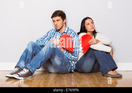 Young couple sitting on floor with broken heart Banque D'Images