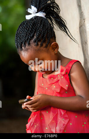 Close up portrait of cute fille africaine de tresses, jouant sur téléphone intelligent. Banque D'Images