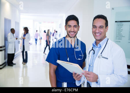 Doctor and nurse smiling in hospital hallway Banque D'Images