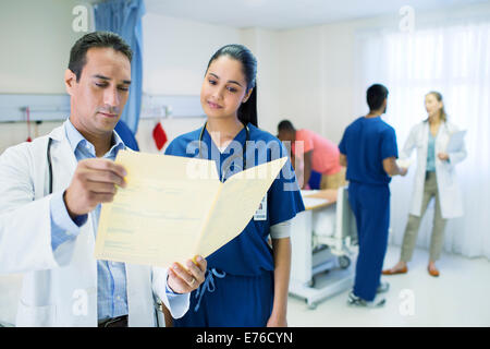 Médecin et infirmière lisant medical chart in hospital room Banque D'Images