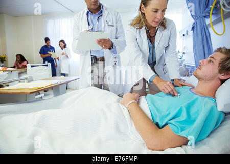 Les médecins examining patient in hospital room Banque D'Images