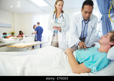 Les médecins examining patient in hospital room Banque D'Images