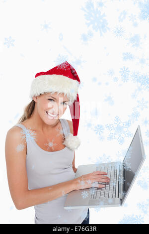 Image composite de femme avec un chapeau de Noël à l'aide d'un ordinateur portable Banque D'Images