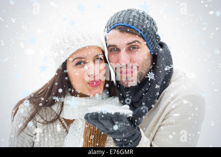 Composite image jeune couple dans des vêtements chauds soufflant Banque D'Images