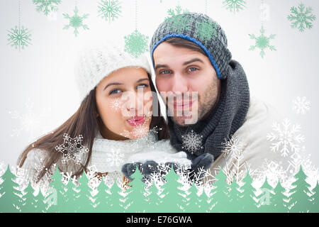 Composite image jeune couple dans des vêtements chauds soufflant Banque D'Images