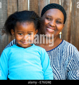 Portrait of African maman et fille contre une clôture en bois.