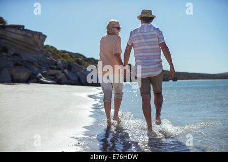 Couple holding hands walking along shore Banque D'Images