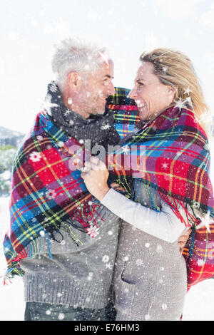 Image composite de l'heureux couple enveloppé dans le contrat cadre debout sur la plage Banque D'Images