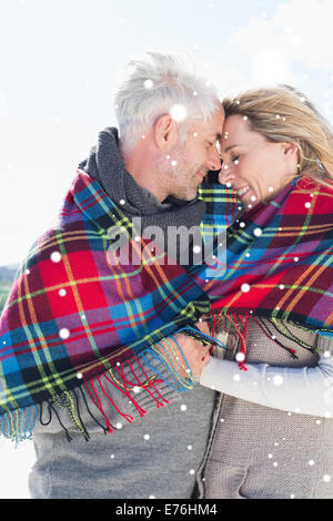 Image composite de l'heureux couple enveloppé dans le contrat cadre debout sur la plage Banque D'Images