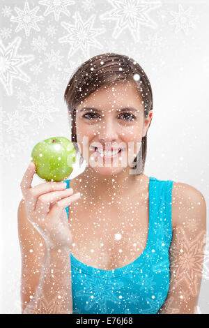 Image composite de jeune femme tenant une pomme verte dans sa main droite Banque D'Images