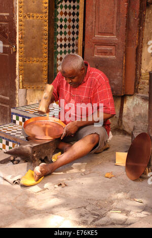 Fes Maroc un artisan local à la place Seffarine au sein de la Medina de prendre une barre de cuivre en battant avec un maillet en bois Banque D'Images