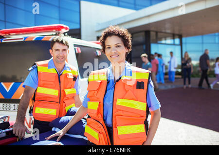 Les ambulanciers smiling par ambulance à l'hôpital stationnement Banque D'Images