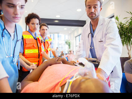 Médecin, infirmières et ambulanciers paramédicaux examining patient in hospital Banque D'Images
