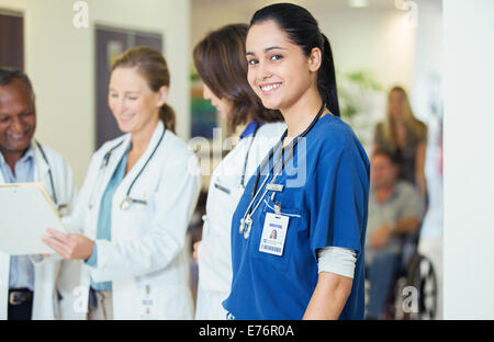 Nurse smiling in hospital hallway Banque D'Images