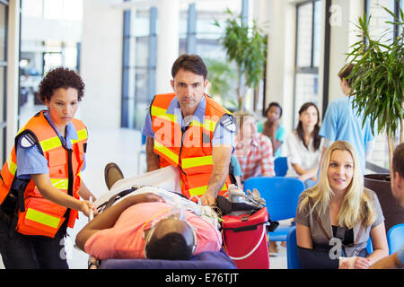 Les ambulanciers wheeling patient in hospital Banque D'Images