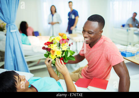 Man giving girlfriend bouquet de fleurs à l'hôpital Banque D'Images