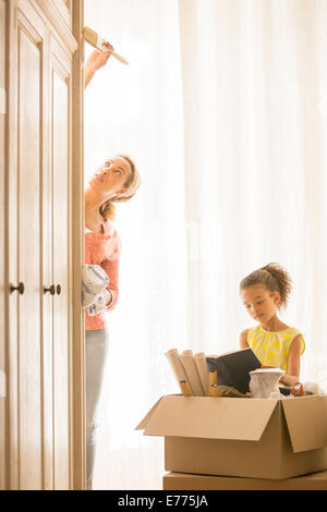 Mère fille peinture armoire avec lecture Banque D'Images