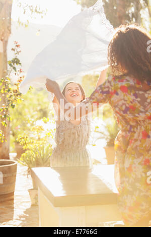 Mère et fille portant table cloth sur table Banque D'Images