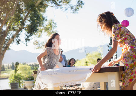 Mère et fille portant table cloth sur table Banque D'Images