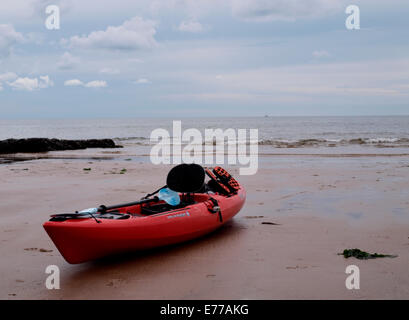 S'asseoir sur le canoë sur la plage, Exmouth, Devon, UK Banque D'Images