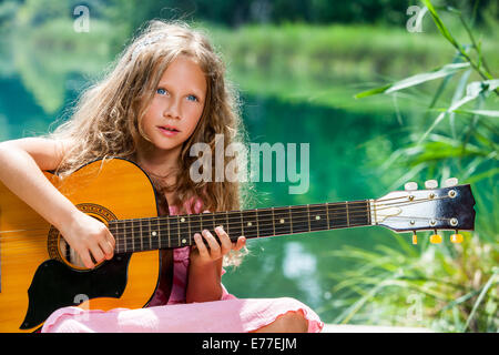 Close up portrait of young étudiant jouant de la guitare espagnole guitare au lac. Banque D'Images