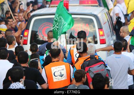 Jérusalem. 8 Septembre, 2014. L'ambulance transportant le corps de l'adolescent tué Muhammad Abd al-Majid Sunuqrut fait son chemin à travers les rues bondées, plein de personnes dans la banlieue de Wadi Al-Joz palestinienne. Un enterrement a eu lieu depuis 16 ans, Muhammad Abd al-Majid Sunuqrut, un adolescent palestinien qui avait été abattu il y a une semaine par les forces israéliennes. Muhammad a été tué, apparemment, à la tête par une balle en caoutchouc par les forces israéliennes à son village dans l'Est de Jérusalem, dans la région de al Wadi Joz. Les forces israéliennes ont affirmé avoir tiré sur l'adolescent dans la jambe. Banque D'Images