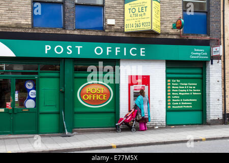 Les femmes asiatiques avec un enfant à l'aide d'un distributeur de billets un distributeur automatique à un bureau de poste à Attercliffe Sheffield South Yorkshire, UK Banque D'Images
