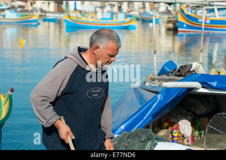 Tôt le matin, au port de Marsaxlokk à Malte où les pêcheurs peuvent être trouvés à assister à leurs bateaux Banque D'Images