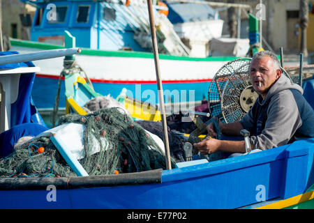 Tôt le matin, au port de Marsaxlokk à Malte où les pêcheurs peuvent être trouvés à assister à leurs bateaux Banque D'Images