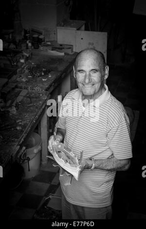 Homme photographié à l'entrée de son atelier où il fait de modèles de bateaux de Vittoriosa, Malte Banque D'Images